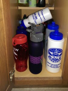 Water bottles in a cabinet, with one on top of the others.