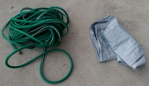 Old green hose and folded-up deflated air mattress.