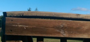 Wooden deck railing, slightly warped.