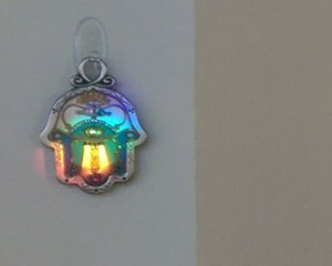 Hamsa wall hanging with rainbow light.