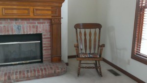 Rocking chair in corner between fireplace and window.