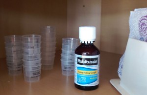 Four stacks of old plastic cough syrup dose cups.