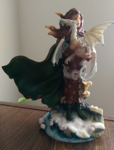 Figurine of fairy holding small white dragon.