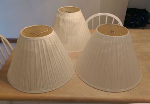 Three old worn-out lampshades on a table.