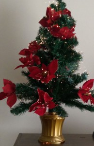 Small artificial holiday tree with red flowers and fiber-optic lights.