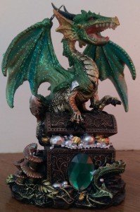 Figurine of a green dragon on a treasure chest.