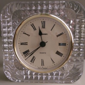 Old clock with analog face in clear plastic case.