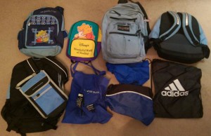 Two rows of old backpacks on brown carpet.