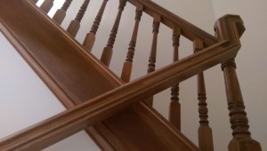 View of wooden banister looking up from lower handrail to upper portion of stairway.