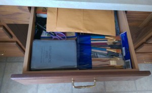 Desk drawer under kitchen counter, full of random stuff.