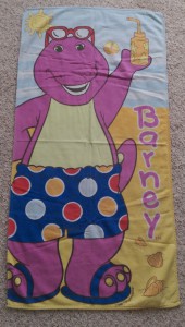 Child's towel with Barney the dinosaur in beach clothing.