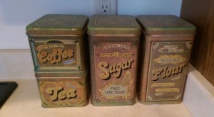 Set of four old metal canisters labeled Coffee, Tea, Sugar, and Flour.