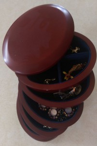 Oval wooden jewelry box with five rotating vertical drawers, partly open.