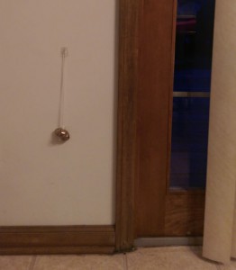 Small bells hanging from a wall next to a sliding glass door.