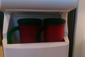 Two red mugs on a shelf in the freezer door.