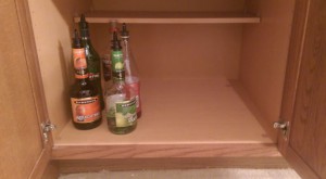 Mostly empty bottles of liquor in a cabinet.