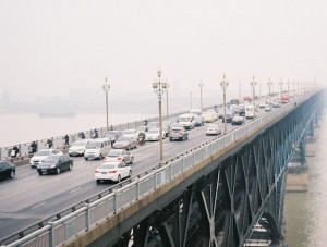 Cars crossing a bridge on a foggy day.