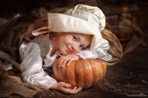 Girl dressed as Cinderella in old-fashioned clothing with a pumpkin.