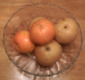 Glass fruit bowl with large mandarin oranges and Asian pears.