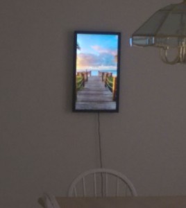 Digital art display on my dining room wall, showing a wooden walkway leading to a beach.