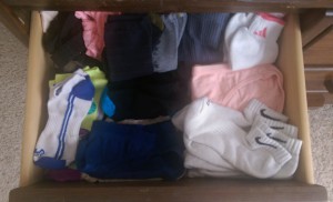 Wooden drawer stacked high with socks of many kinds.