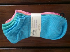 Pack of new socks in assorted pastel colors, on top of my dresser.