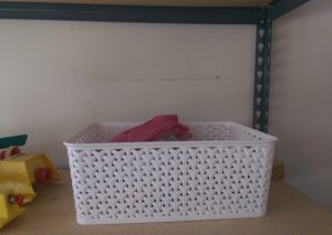 White plastic lattice-weave basket on garage shelf.