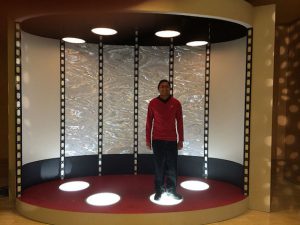 Person in a Star Trek uniform standing on a transporter.