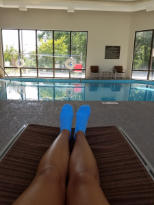 Hotel pool and my tanned legs on a lounge chair.
