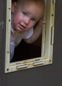 Baby looking through a doggie door.