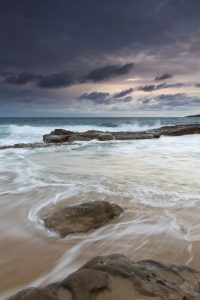 Storm over the ocean with waves breaking against rocks.