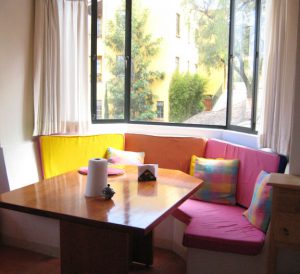 Sunny breakfast nook with brightly colored cushions on a bench.