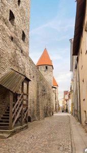 Narrow cobblestone street between stone and wood buildings.