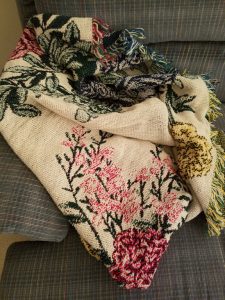 Blanket with floral pattern on couch.