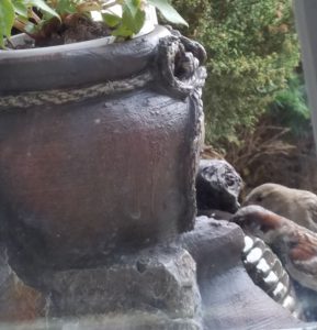 Two birds drinking from a water fountain.