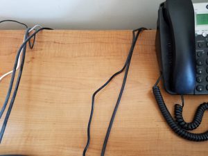 Empty space on a desk with cords and a telephone.