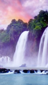 Waterfalls under colorful clouds.