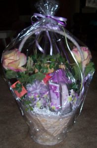 Photo of gift basket wrapped in plastic with purple ribbons.