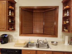 Kitchen window with shelves holding food in jars and boxes.