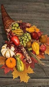 Thanksgiving cornucopia with harvest fruits and autumn leaves.