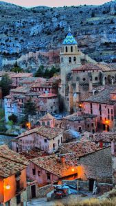 City rooftops framed by a blue-shadowed hillside.