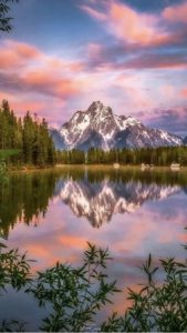 Still waters of a lake reflecting a snowy mountaintop.