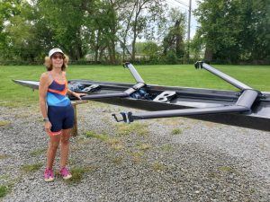 Meg standing next to a double scull on slings.