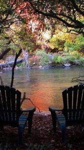Photo of two chairs facing a river.