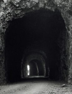 Photo of a tunnel entrance on a dirt road.