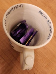 Photo of a mug with the words "Avoid Assumptions" and "Leave Space for Improvement."