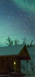 Photo of a snowy cabin at night with a greenish sky.