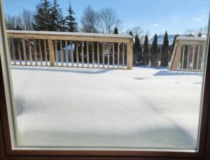 Photo of snow on my deck, taken through the patio door.